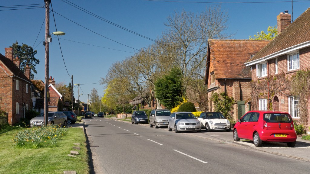 From original photo position, view of chimney of power station above village houses is blocked by large trees
