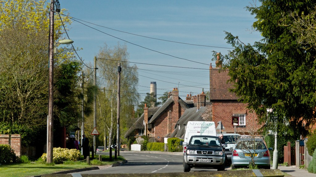 Chimney rises in distance above roofs of houses in village