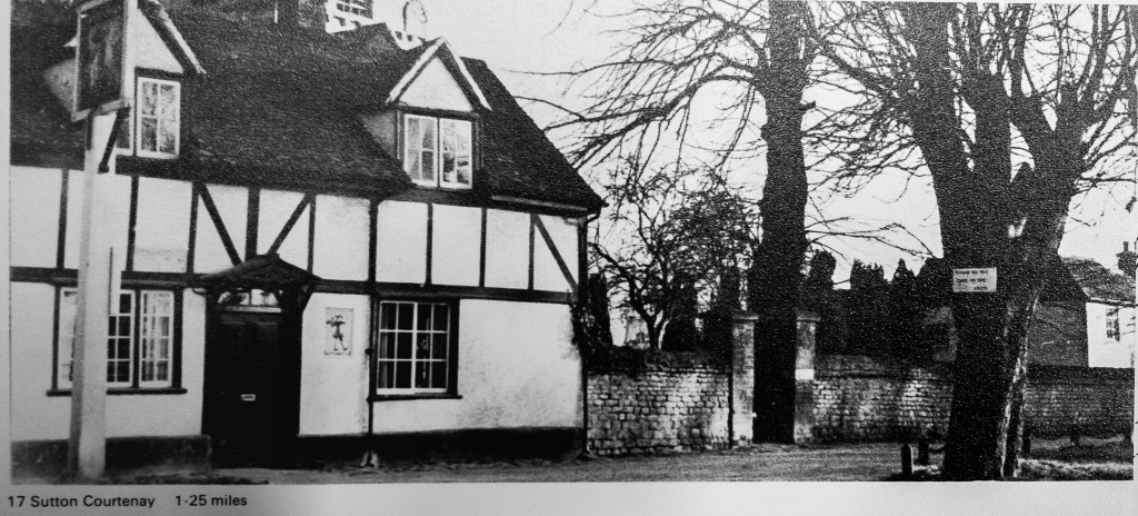 Black and white photo of timber framed pub with church tower behind