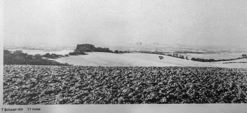 Black and white photo with small cooling towers drawn on in the distance. A small oak tree in the foreground view from the high hill